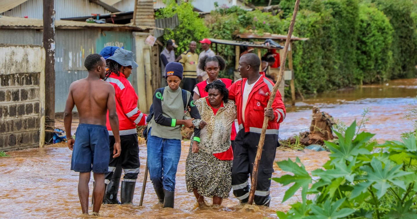 Punaisen Ristin vapaaehtoiset auttavat henkilöä tulvassa.