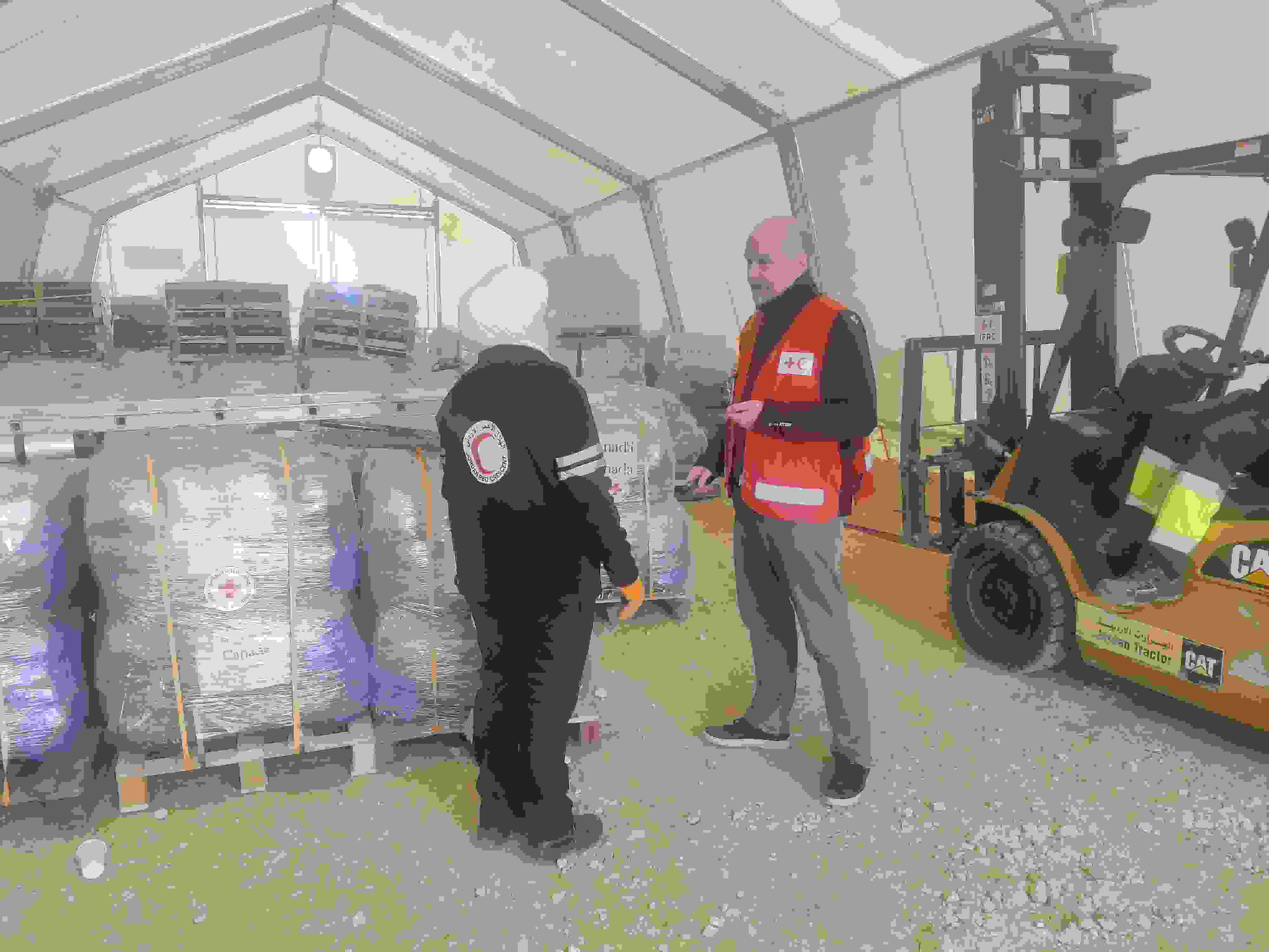 Jordanian Punaisen Puolikuun ja Suomen Punaisen Ristin työntekijät juttelevat Jordaniassa avustustarvikkeiden varastossa