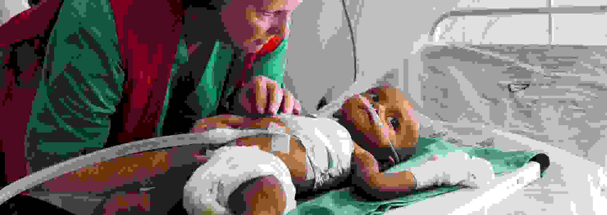 Punaisen Ristin avustustyöntekijä huolehtii vauvasta kenttäsairaalassa.
