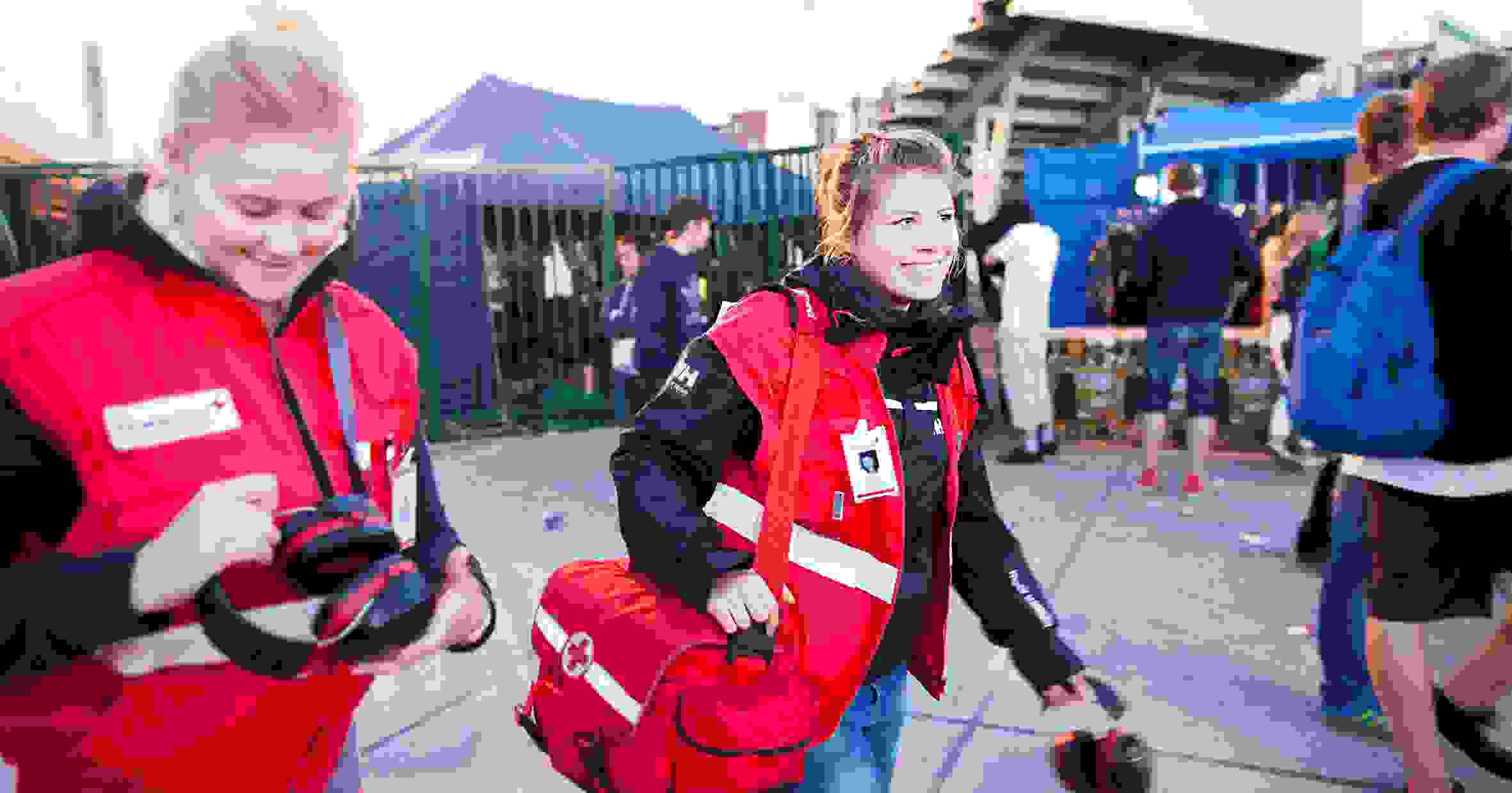 Hymyilevät Punaisen Ristin vapaaehtoiset ensiapupäivystäjät kävelevät festarialueella.