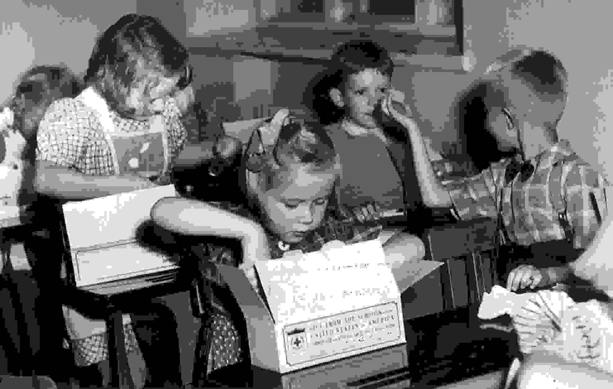 Lapsia avaamassa tarvikepaketteja pulpettiensa ääressä.