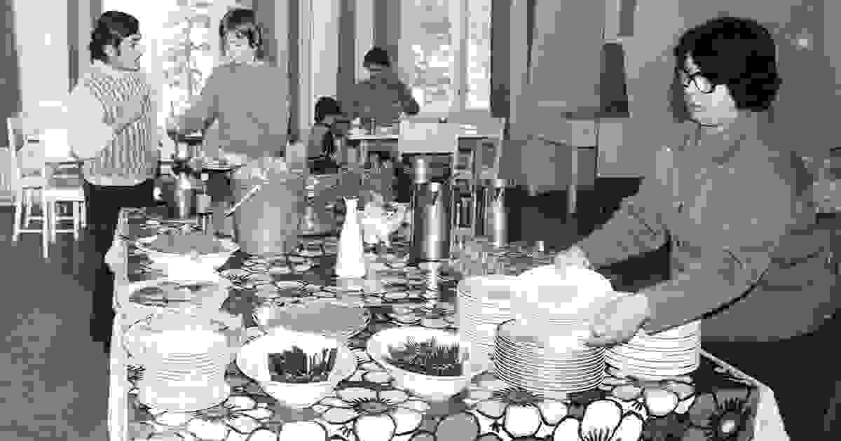 Naisia, miehiä ja lapsi ruokailemassa vastaanottokeskuksessa.