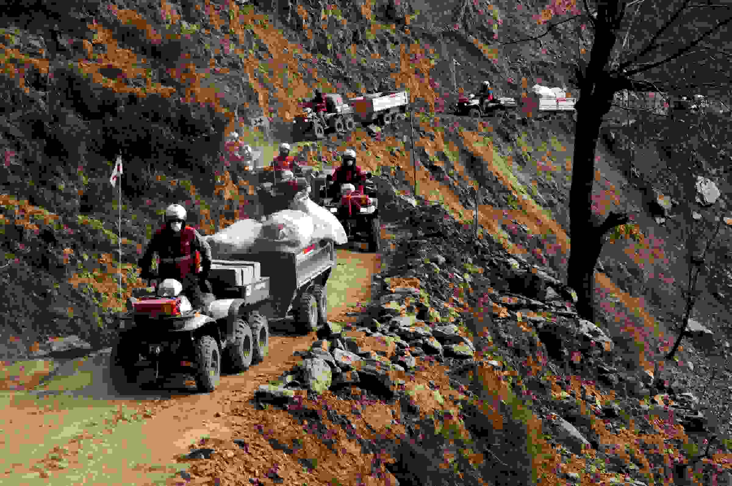 Kuusi Punaisen Ristin mönkijää kuljettaa avustustarvikkeita kapealla vuoristotiellä.