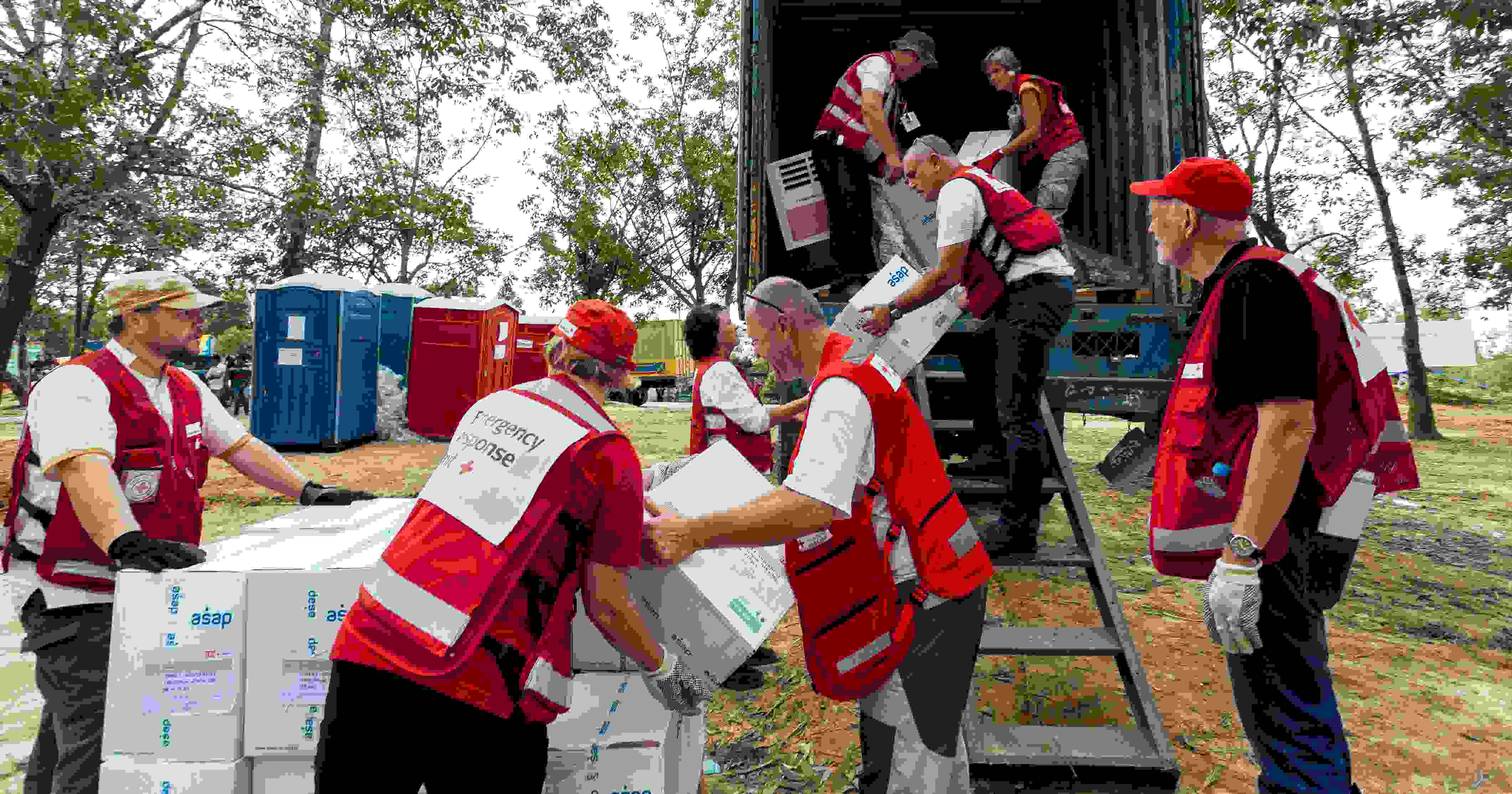 Punaisen Ristin avustustyöntekijät purkavat tarvikkeita autosta.