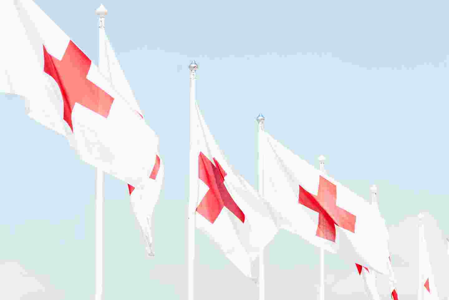 Punaisen Ristin lippuja liehumassa lipputangossa.