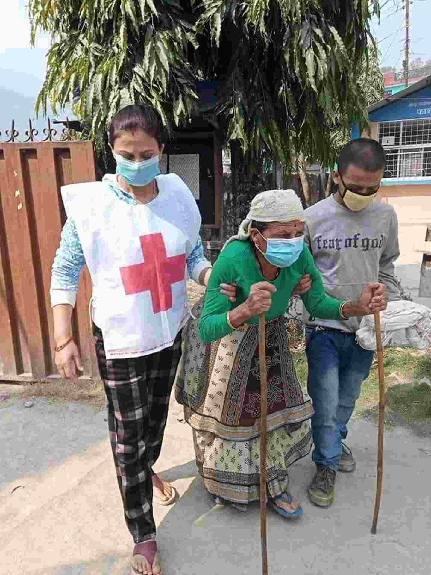Nepalin Punaisen Ristin vapaaehtoiset auttavat iäkästä naista. 