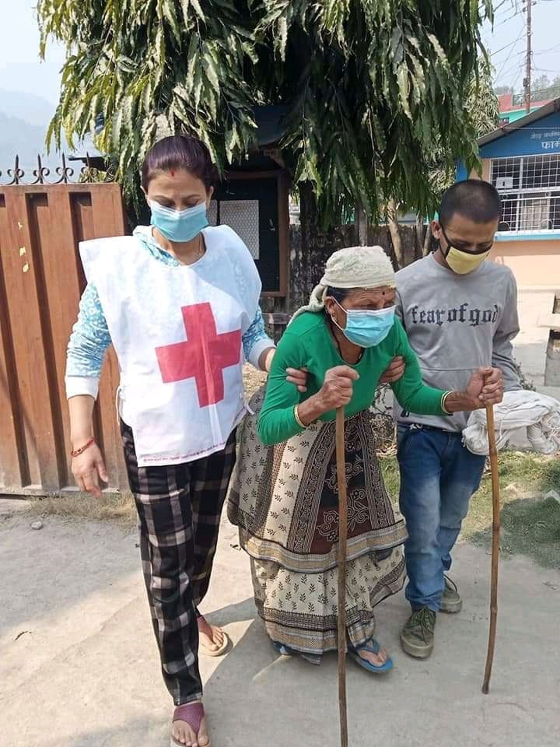 Nepalin Punaisen Ristin vapaaehtoiset auttavat iäkästä naista.