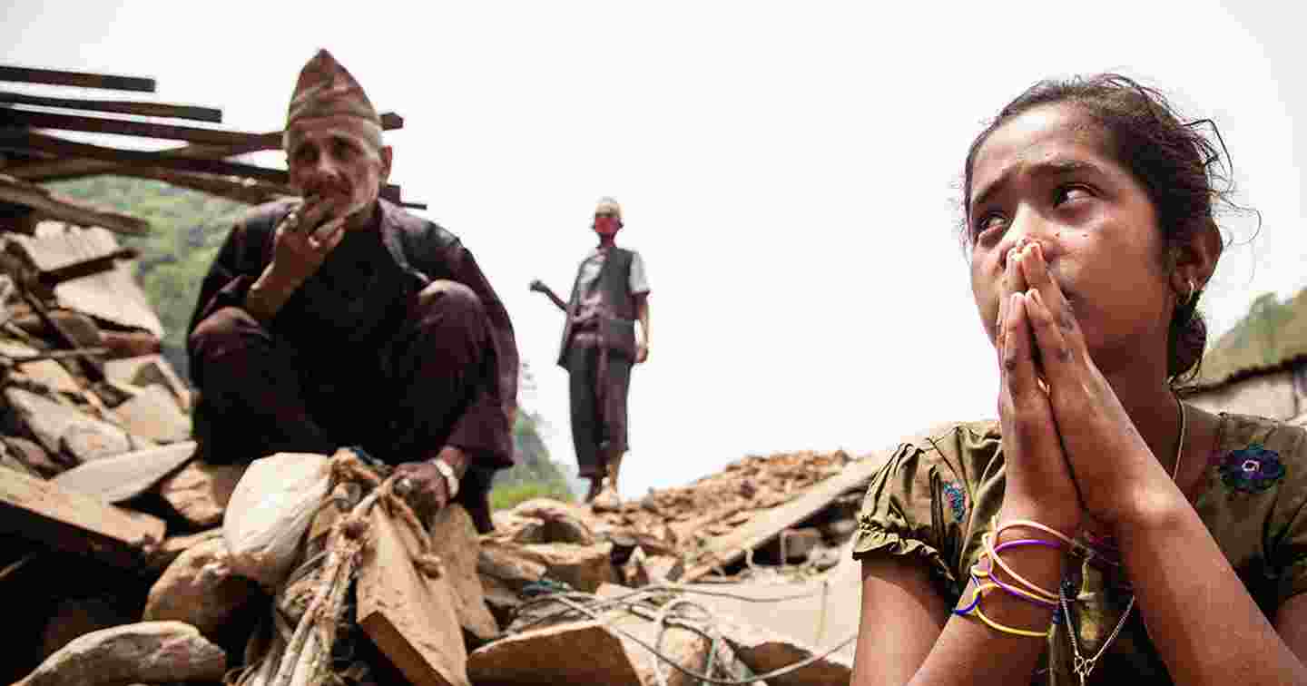 Iäkäs mies ja nuori nainen tuhoutuneen talonsa raunioiden päällä Nepalissa.