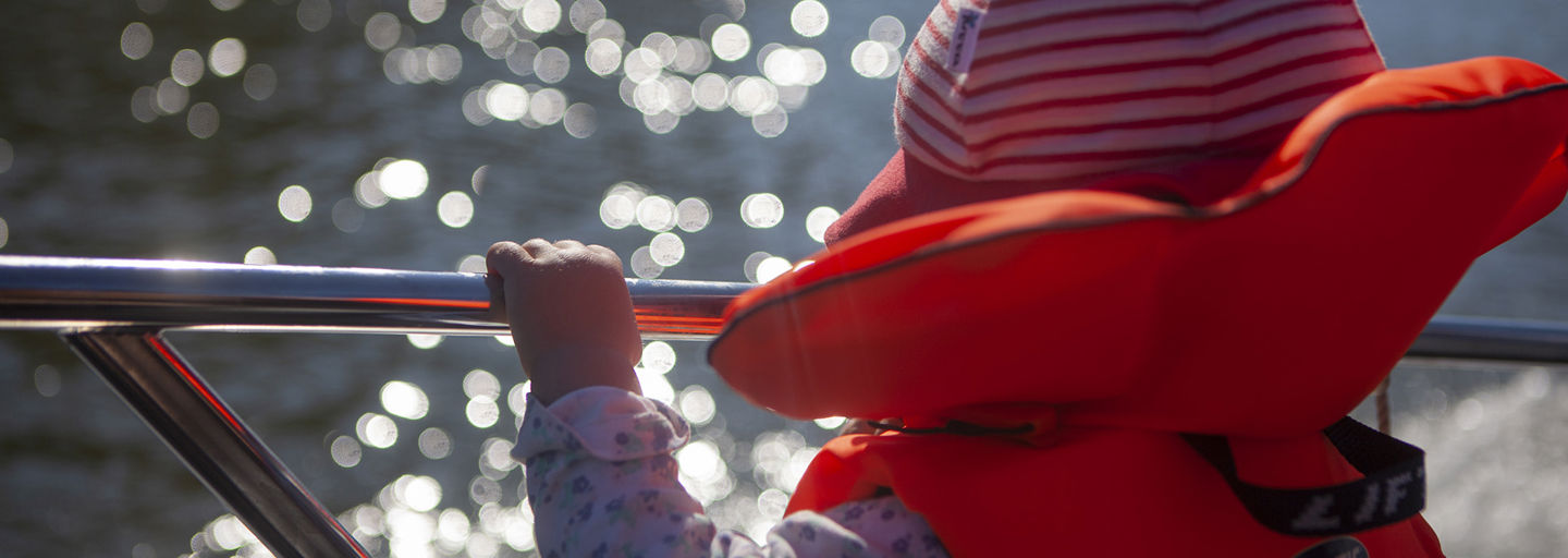 Nuori nainen katsoo eteenpäin yllään Punaisen Ristin vapaaehtoisen liivi. Taustalla on muita vapaaehtoisia.