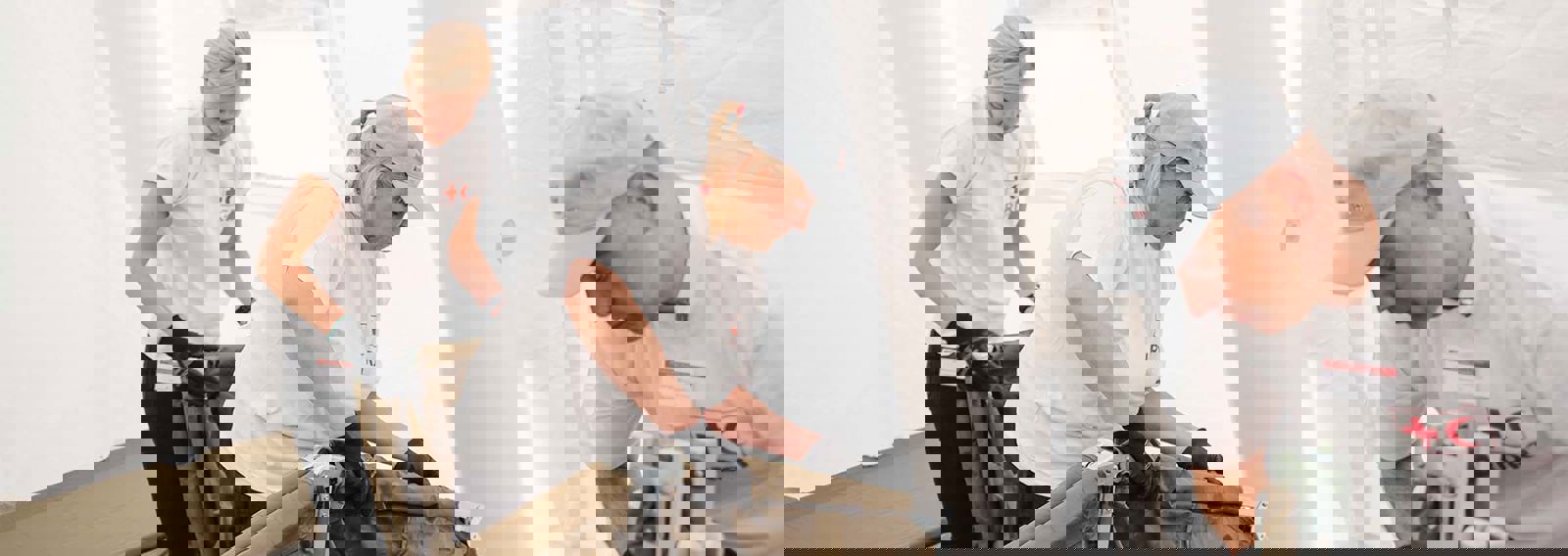 Kolme henkilöä Punaisen Ristin paidoissa pystyttää telttaa.