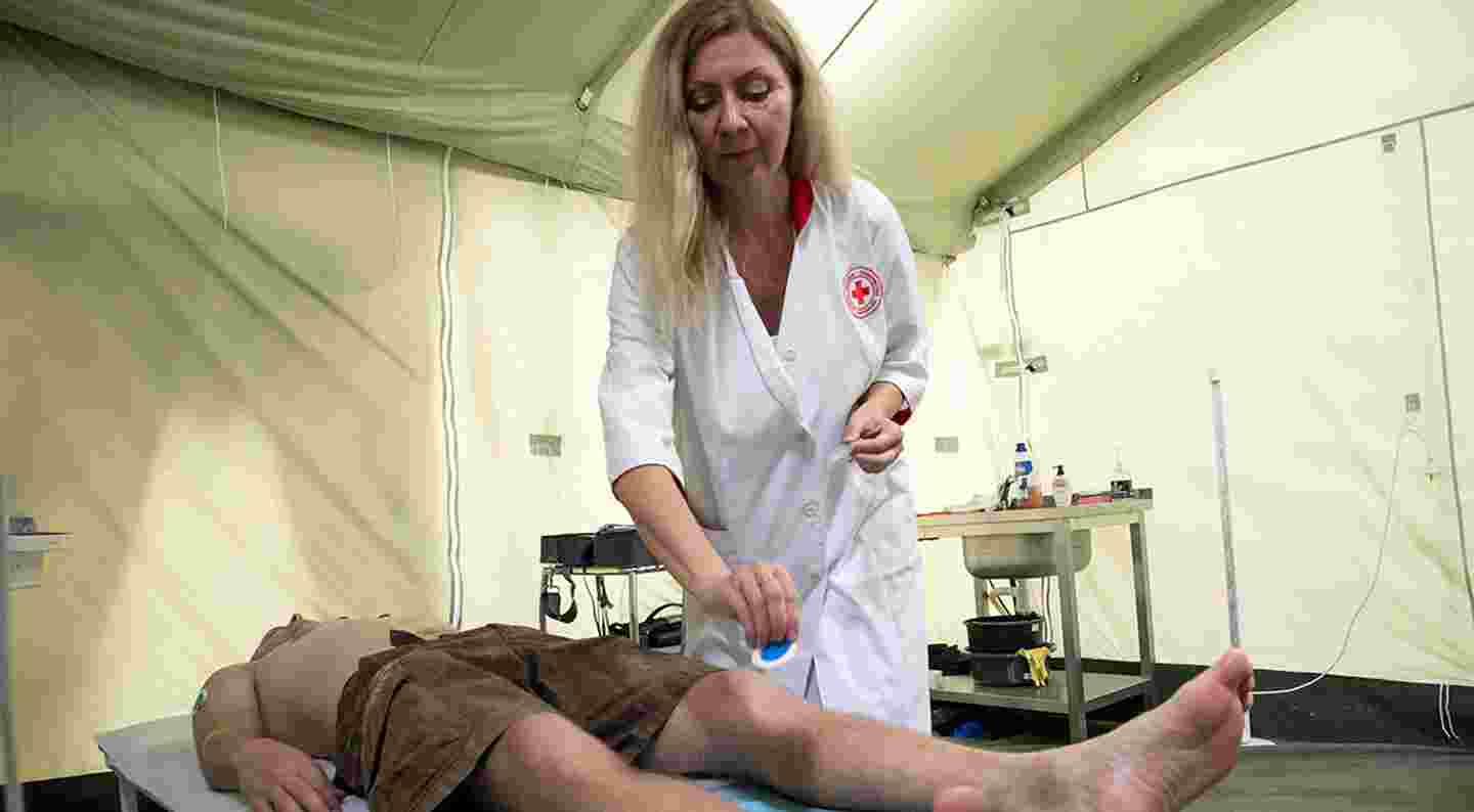 Lääkäri hoitaa potilasta terveysklinikka-teltassa.