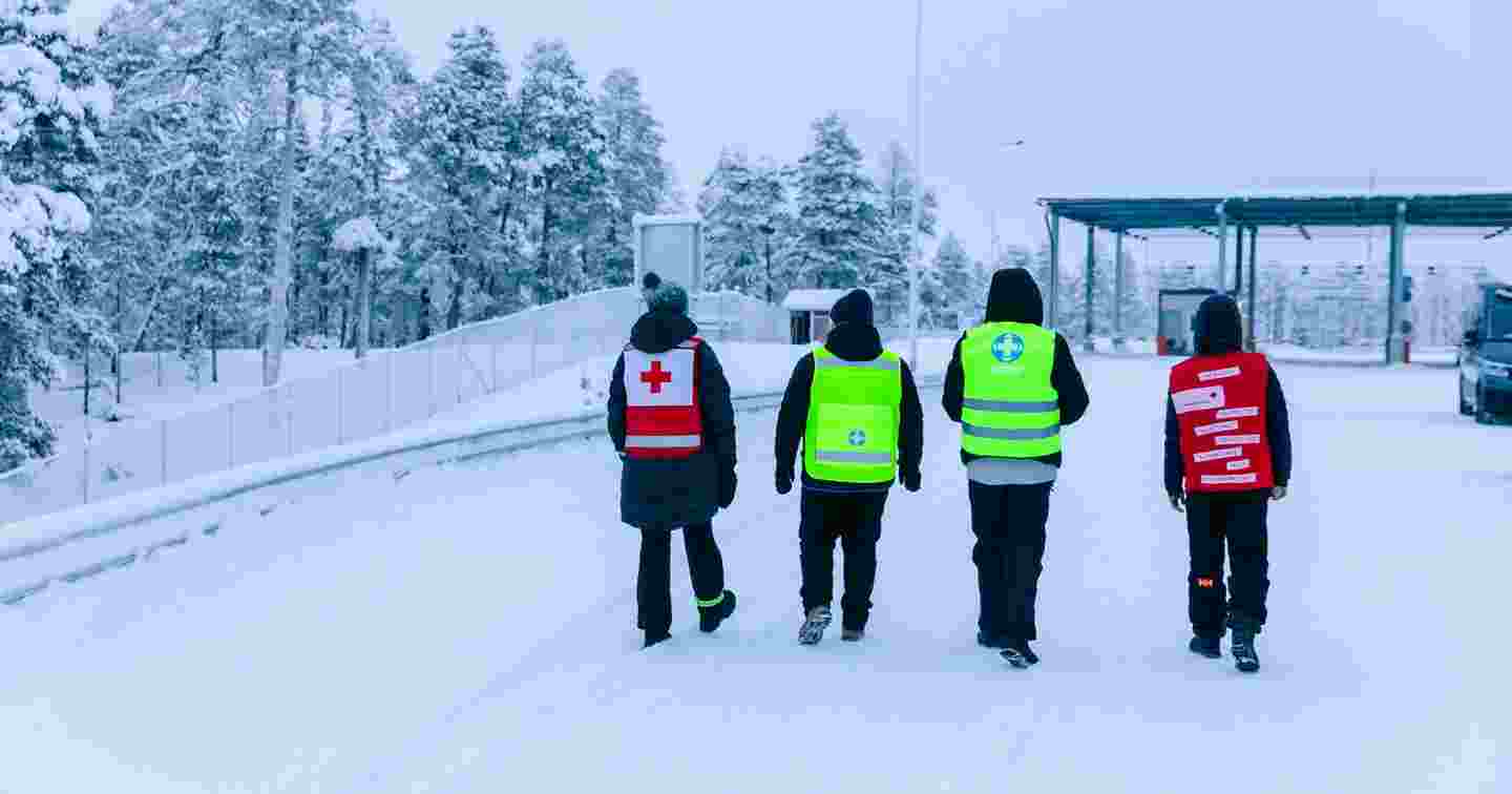 Kaksi Punaisen Ristin ja kaksi Vapaaehtoisen pelastuspalvelun vapaaehtoista kävelee talvisessa maisemassa rajan läheisyydessä.