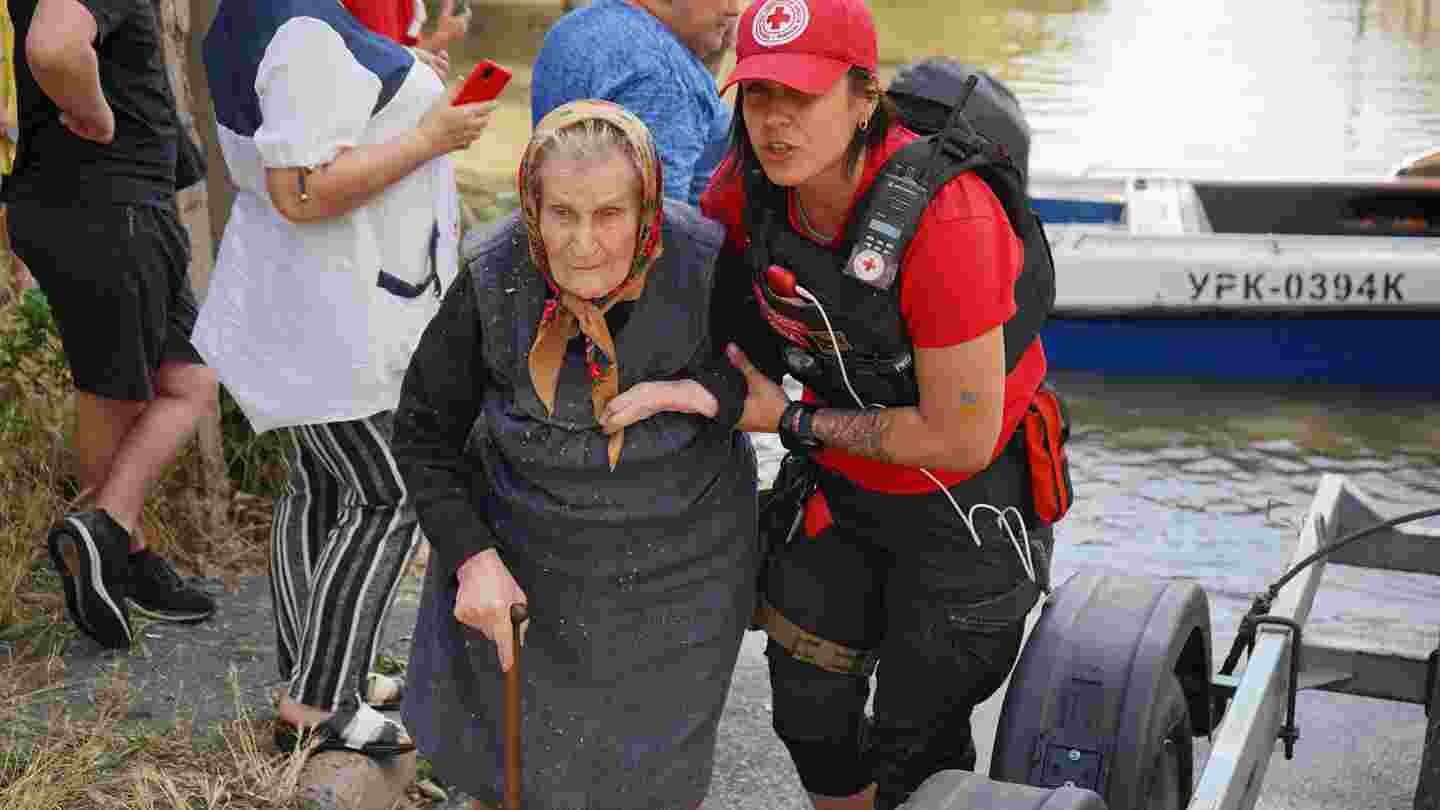 Ukrainan Punaisen Ristin vapaaehtoinen auttaa iäkästä henkilöä kävelemään.