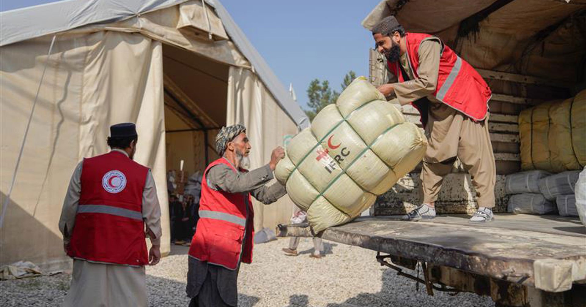 Afganistanin Punaisen Puolikuun vapaaehtoiset siirtävät avustuspakettia kuorma-autosta teltalle katastrofialueella.