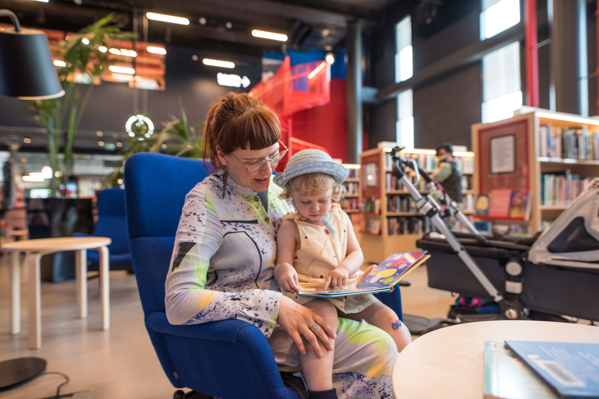 Lapsi lukee kuvakirjaa aikuisen sylissä