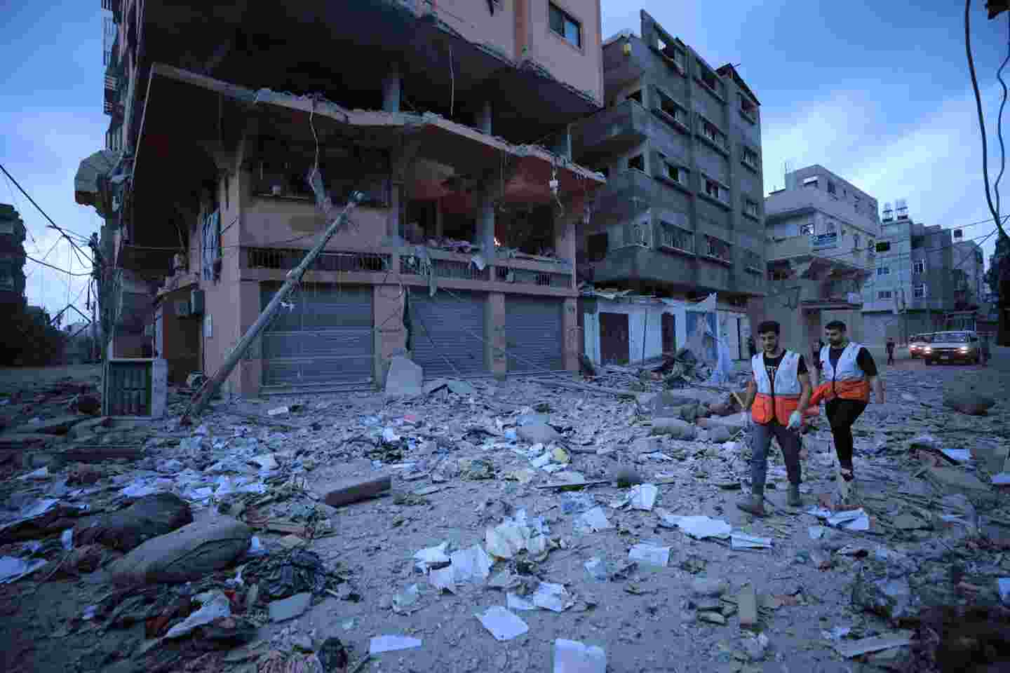 Palestiinan Punaisen Puolikuun vapaaehtoisia tekemässä avustustyötä raunioituneiden rakennusten keskellä.