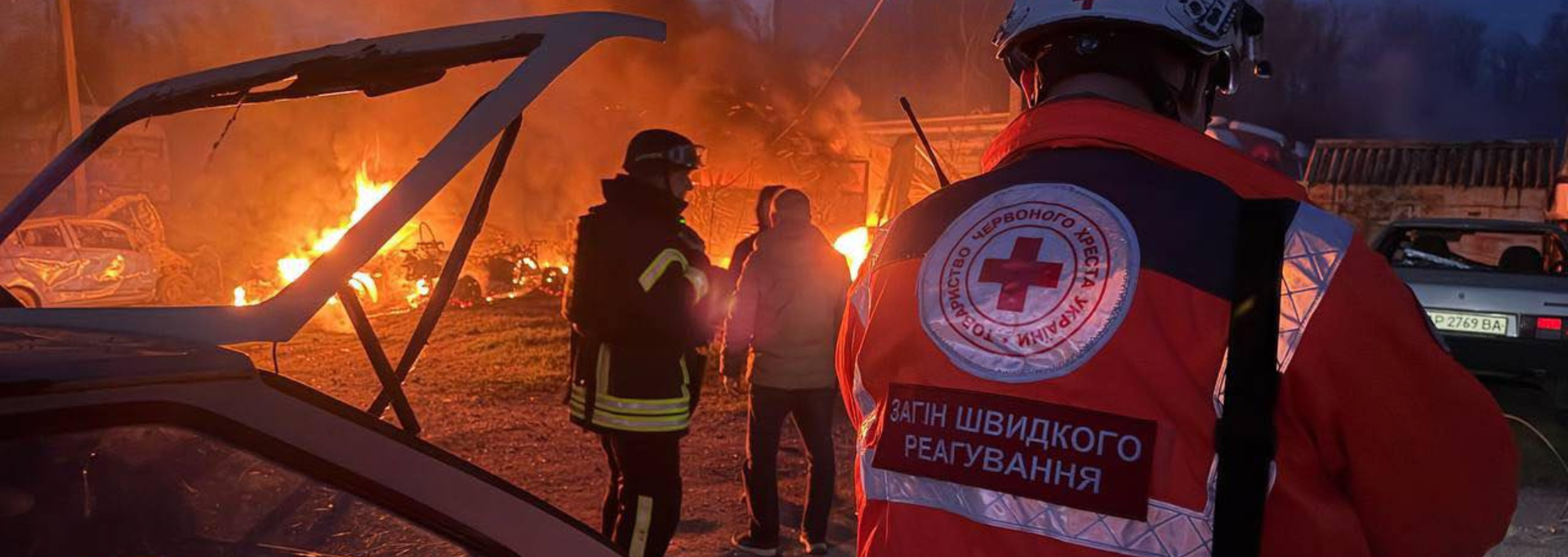 Ukrainan Punaisen Ristin vapaaehtoinen auttaa iäkästä naista kävelemään.
