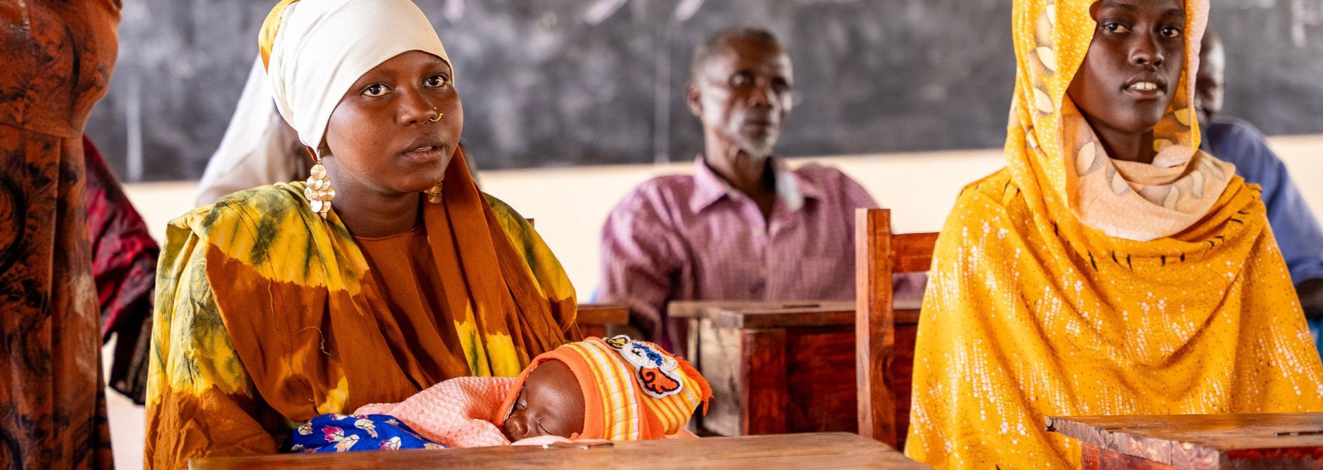 Kaksi Punaisen Ristin vapaaehtoista punaisissa keräysliiveissä käsissään keräyslippaat. Vieressä noin kaksi metriä pitkä keräyslipas.