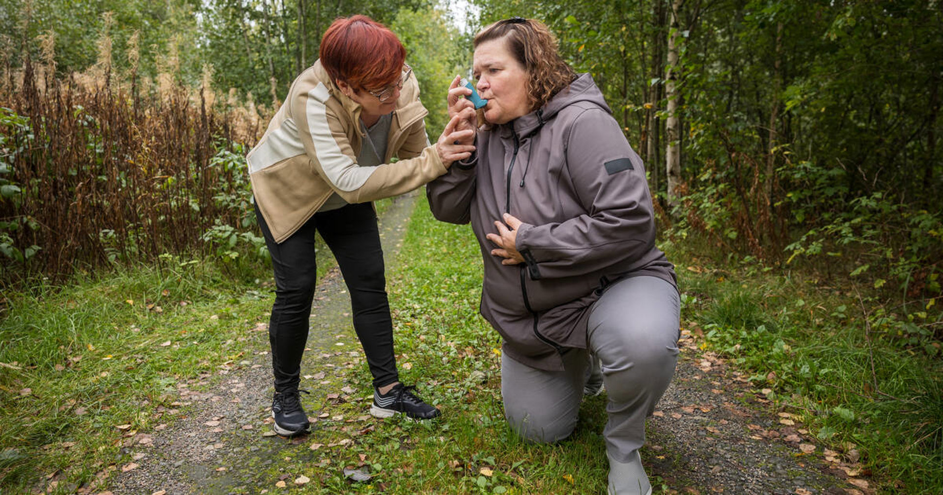 Henkilö haukkoo henkeään vierellään auttaja, joka pitää kättään tämän olkapäällä.