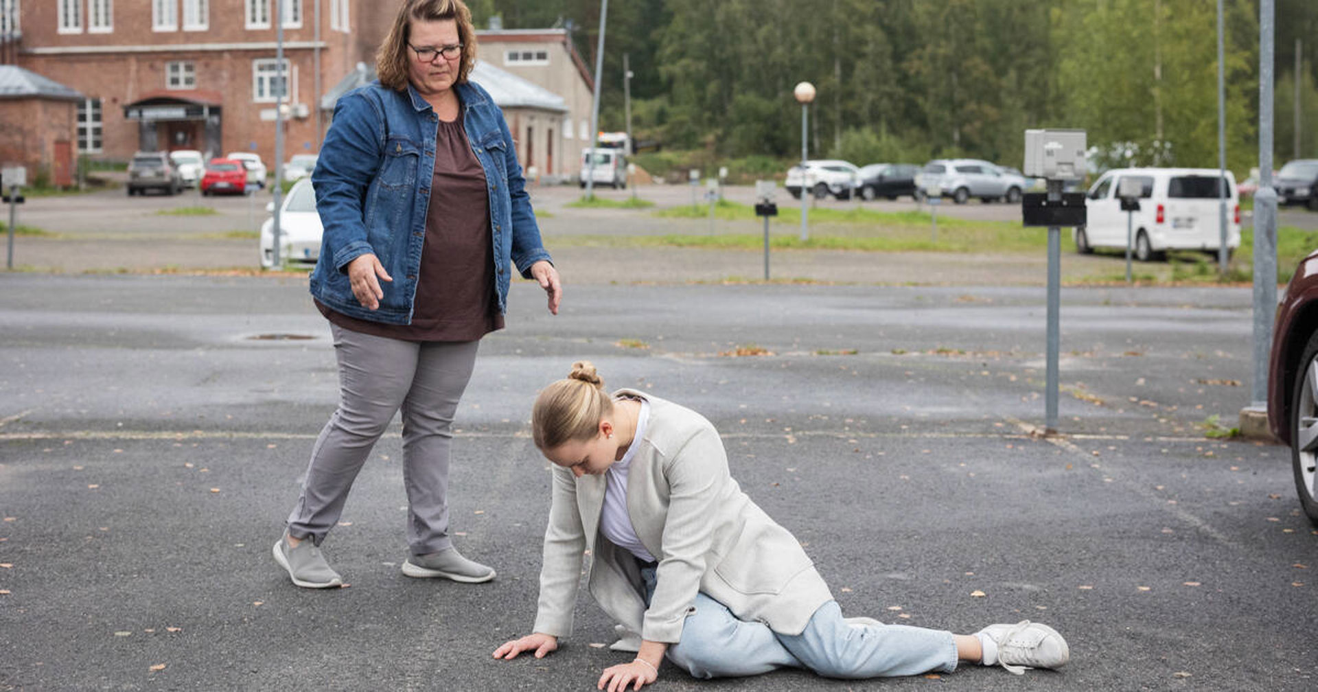 Henkilö polvillaan kerrostalon sisäpihalla.