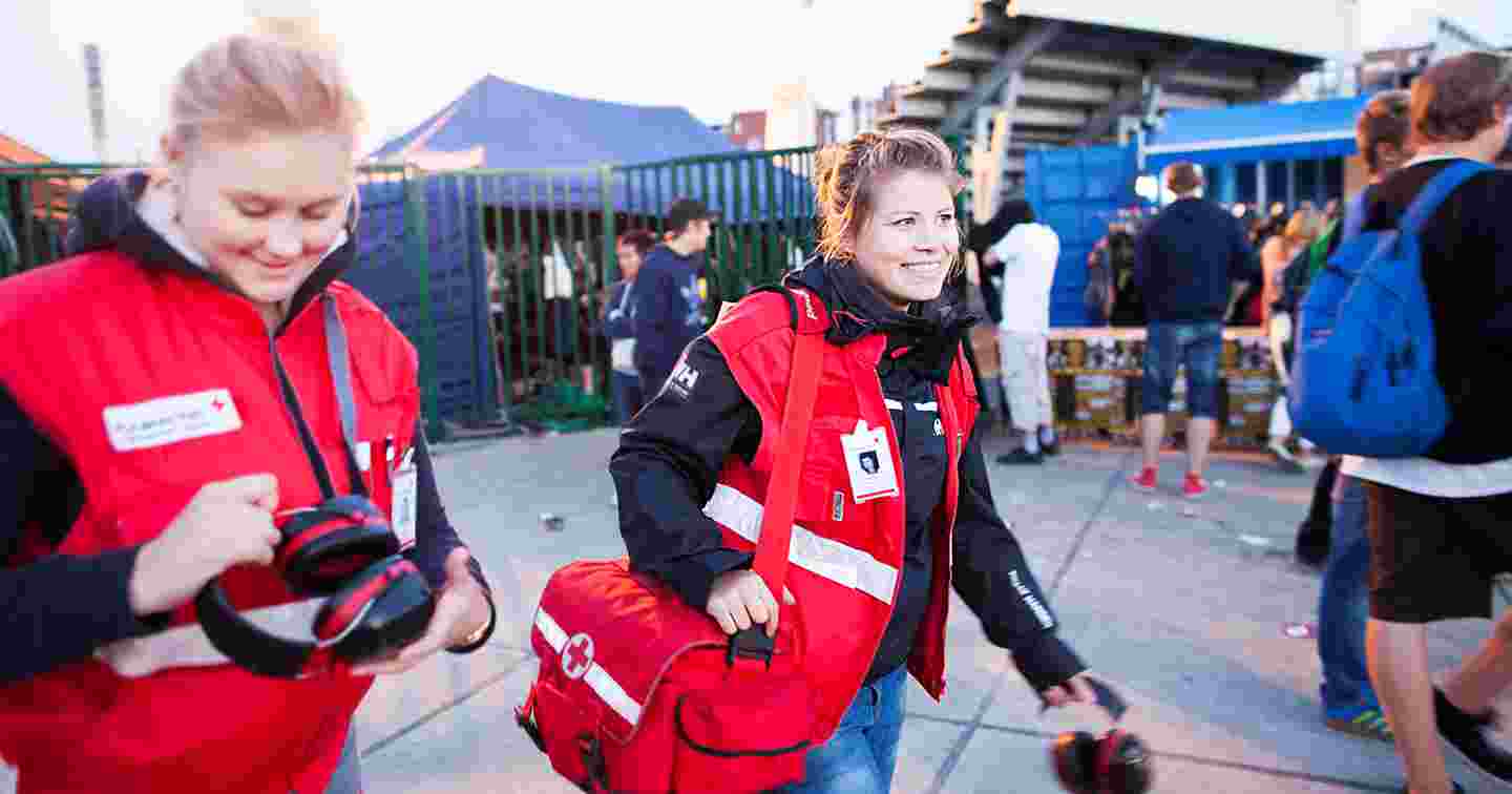 Hymyilevät Punaisen Ristin vapaaehtoiset ensiapupäivystäjät kävelevät festarialueella.