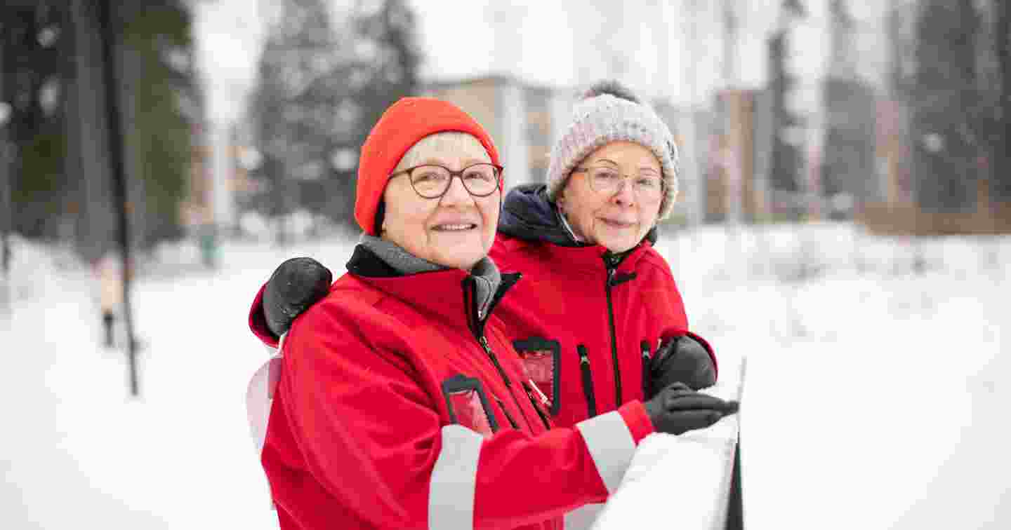 Punaisen Ristin vapaaehtoiset Tuuli Sundell ja Leena Valtee-Kuuskoski hymyilevät vierekkäin talvisessa maisemassa.