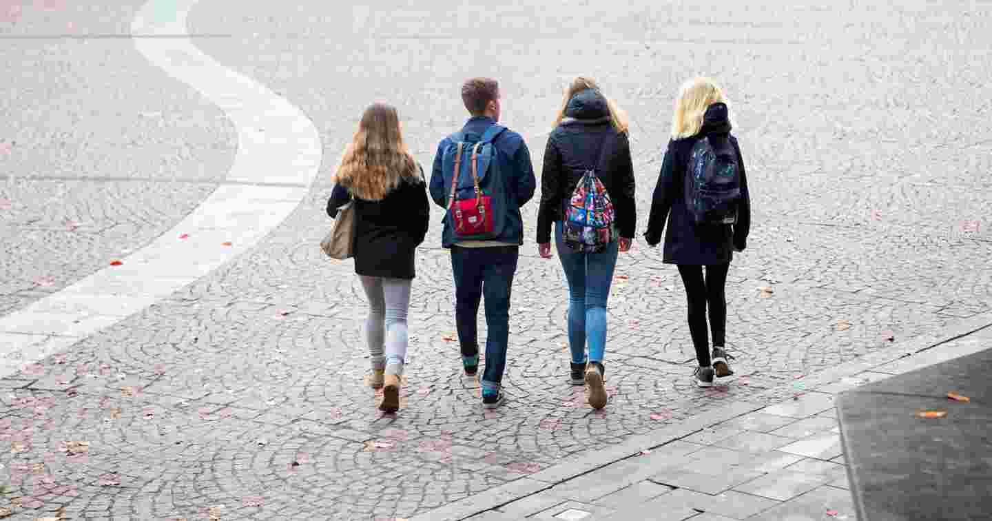 Neljä nuorta kävelee ulkona syksyisessä säässä.