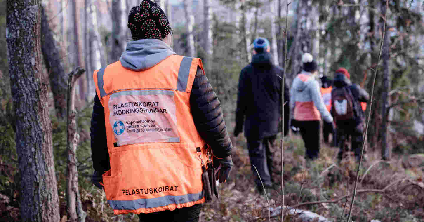 Vapaaehtoisen pelastuspalvelun liiveihin sonnustautuneita vapaaehtoisia osallistuu etsintäharjoituksiin talvisessa metsässä.