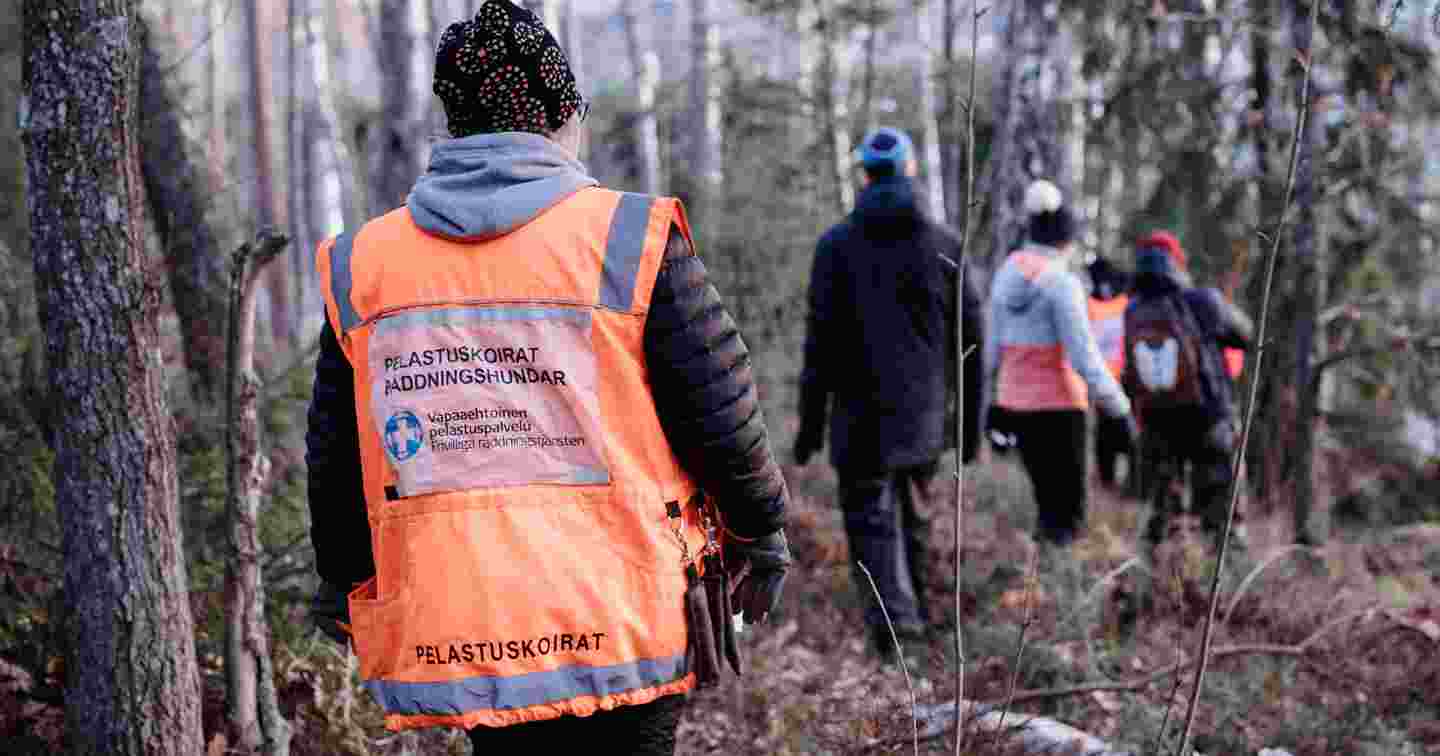 Vapaaehtoisen pelastuspalvelun liiveihin sonnustautuneita vapaaehtoisia osallistuu etsintäharjoituksiin talvisessa metsässä.