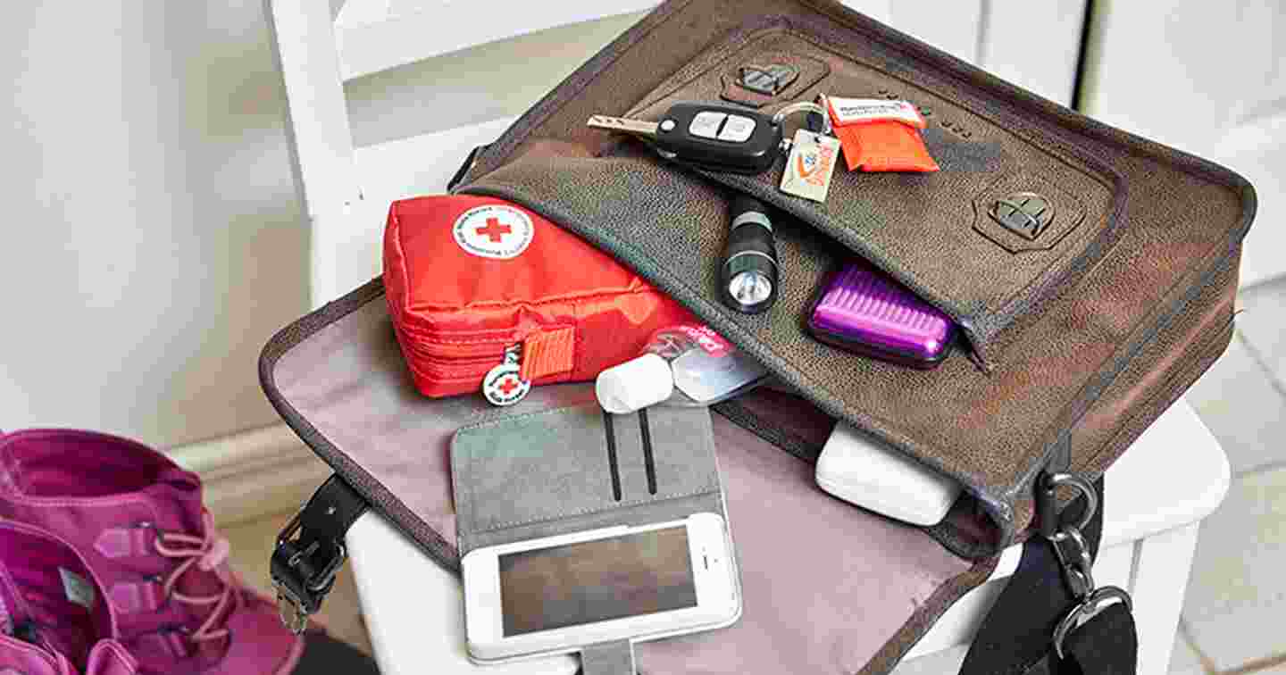 Laukku täynnä varautumiseen tarvittavia tarvikkeita, kuten ensiapulaukku, puhelin, taskulamppu ja käsidesiä.