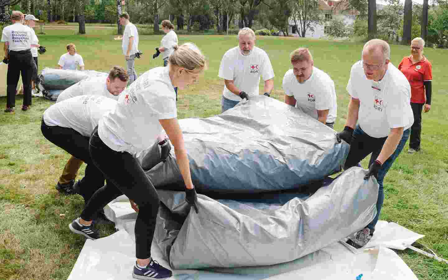 Punaisen Ristin vapaaehtoiset pystyttävät telttaa.