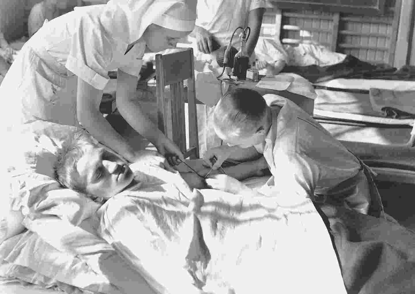 Lääkäri ja sairaanhoitaja suorittavat verensiirtoa sairaalavuoteella makaavalle miespotilaalle.