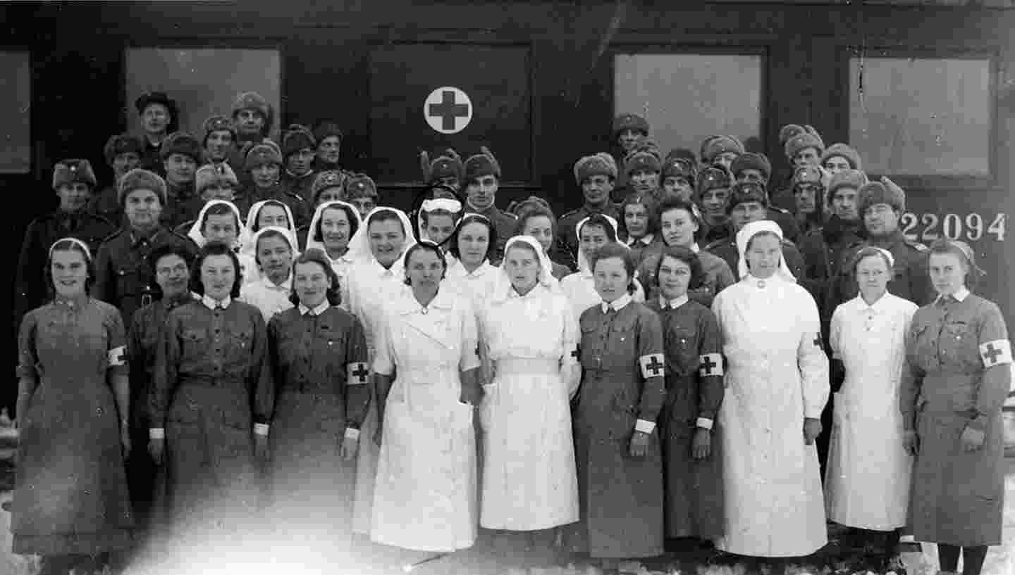 Parikymmentä Punaisen Ristin sairaanhoitajaa sonnustautuneina Punaisen Ristin asuihin ja hihamerkkeihin.