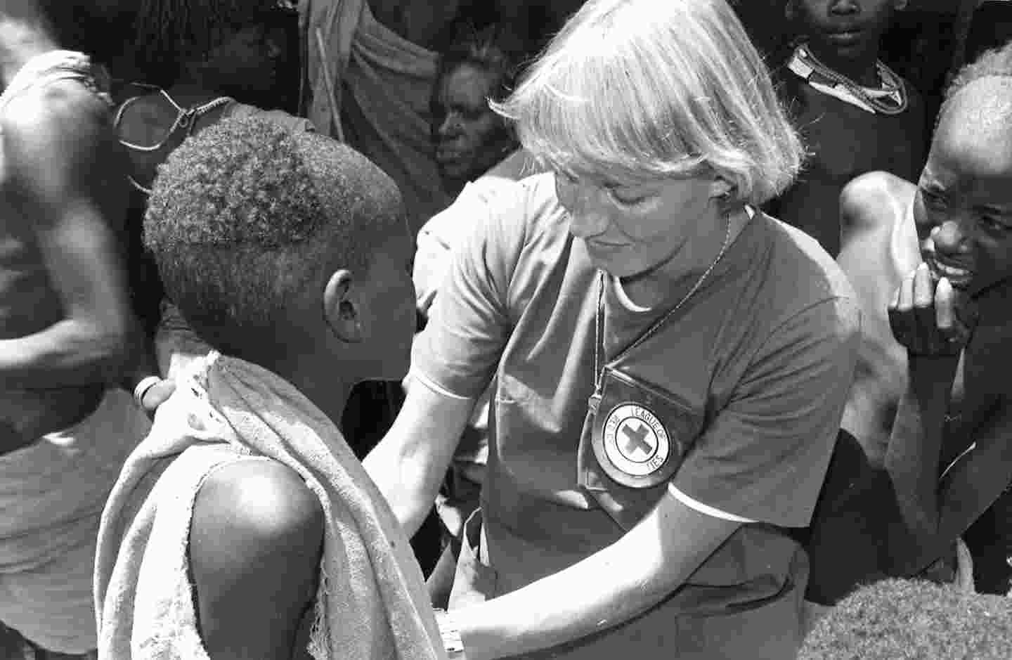 Punaisen Ristin avustustyöntekijä hoitaa afrikkalaista naista.