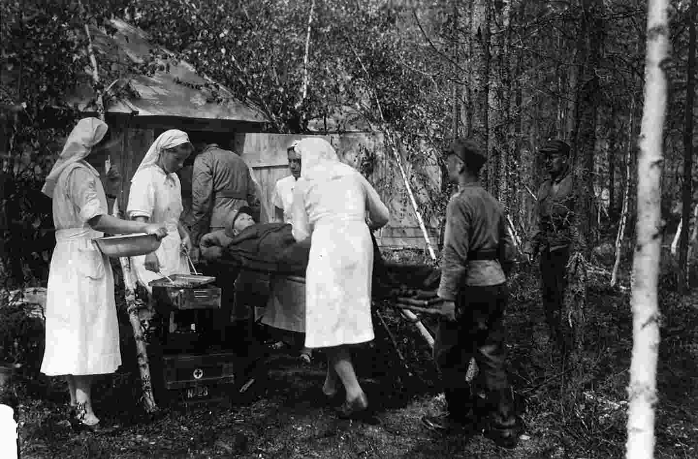 Haavoittunutta tuodaan kenttäsairaalaan. SPR:n sairaanhoitajilla oli Mannerheimin määräyksestä hunnut.
