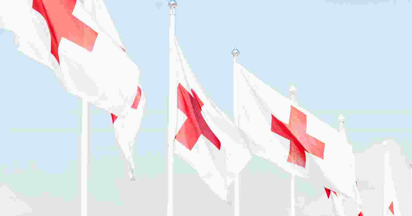 Kuusi Punaisen Ristin lippua lipputangoissa.
