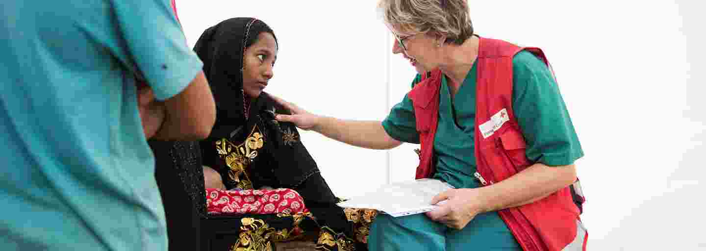 Nuori bangladeshilainen nainen keskustelee Punaisen Ristin avustustyöntekijän kanssa kenttäsairaalassa.