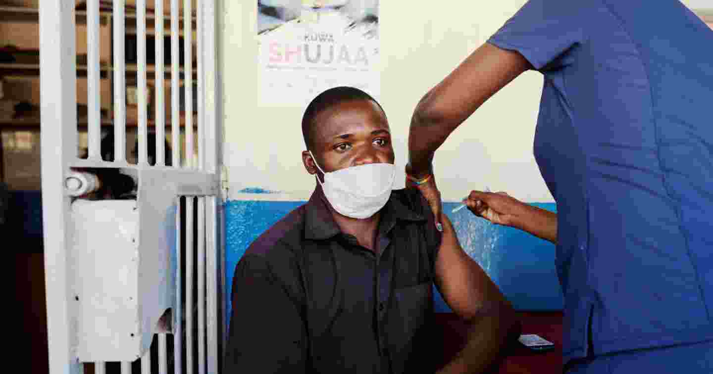 Miehen käsivarteen pistetään rokotetta.