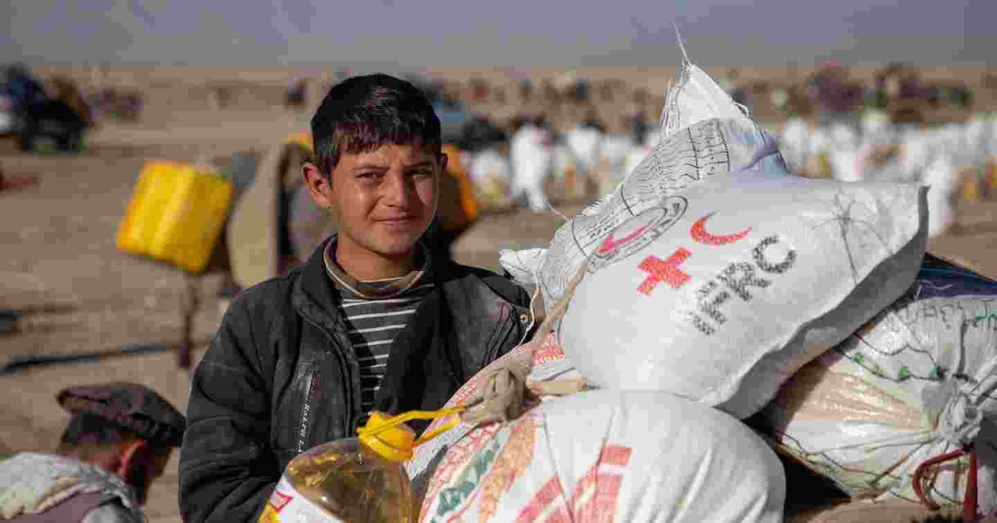 Afganistanilainen nuori noutamassa  Punaisen Ristin avustustarvikkeita.