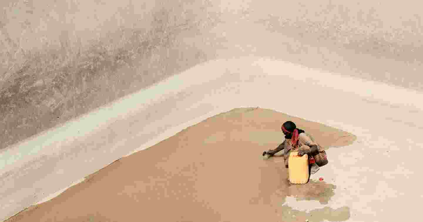 Nainen hakee vettä suuren vesialtaa pohjalta. Altaan pohjalla on enää pieni lammikko.