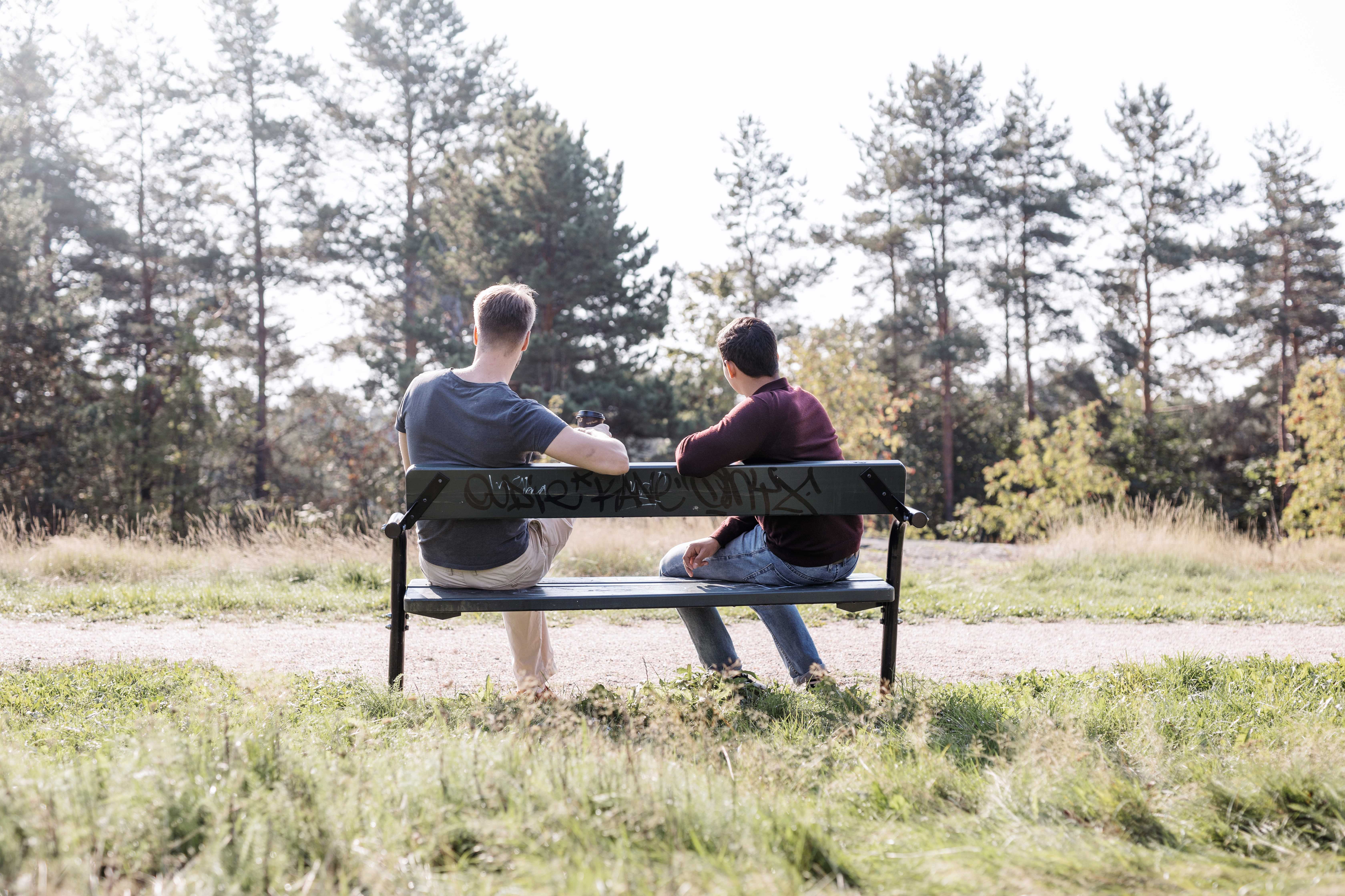 Kaksi nuorta istuu penkillä selin katsojaan. 