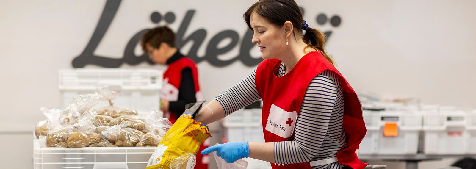Kaksi Punaisen Ristin vapaaehtoista lajittelee ruoka-apua.