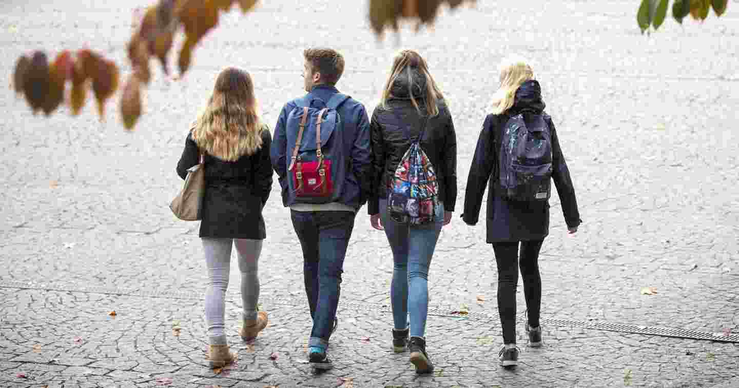 Neljä nuorta kävelee vierekkäin reput selässä. 