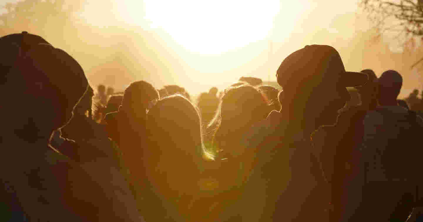 Nuorten juhlijoiden siluetti festivaali-illan auringonlaskussa.