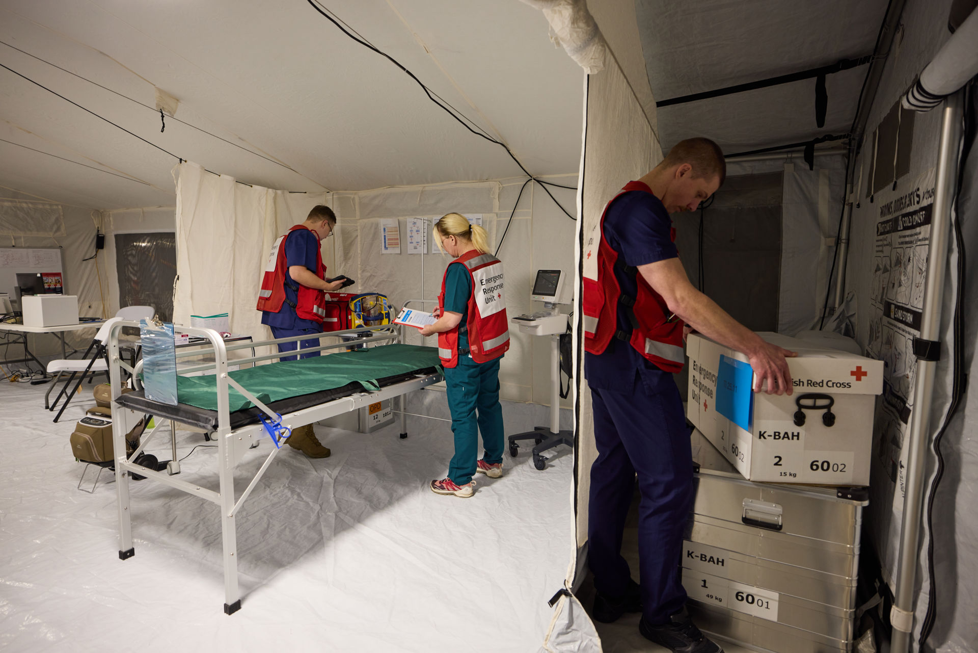 Sairaalan henkilökunta hoitaa potilasta Punaisen Ristin kenttäsairaalan teltassa