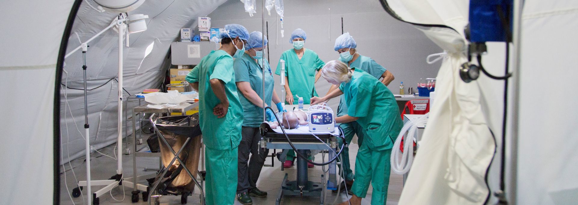 Sairaalan henkilökunta hoitaa potilasta Punaisen Ristin kenttäsairaalan teltassa