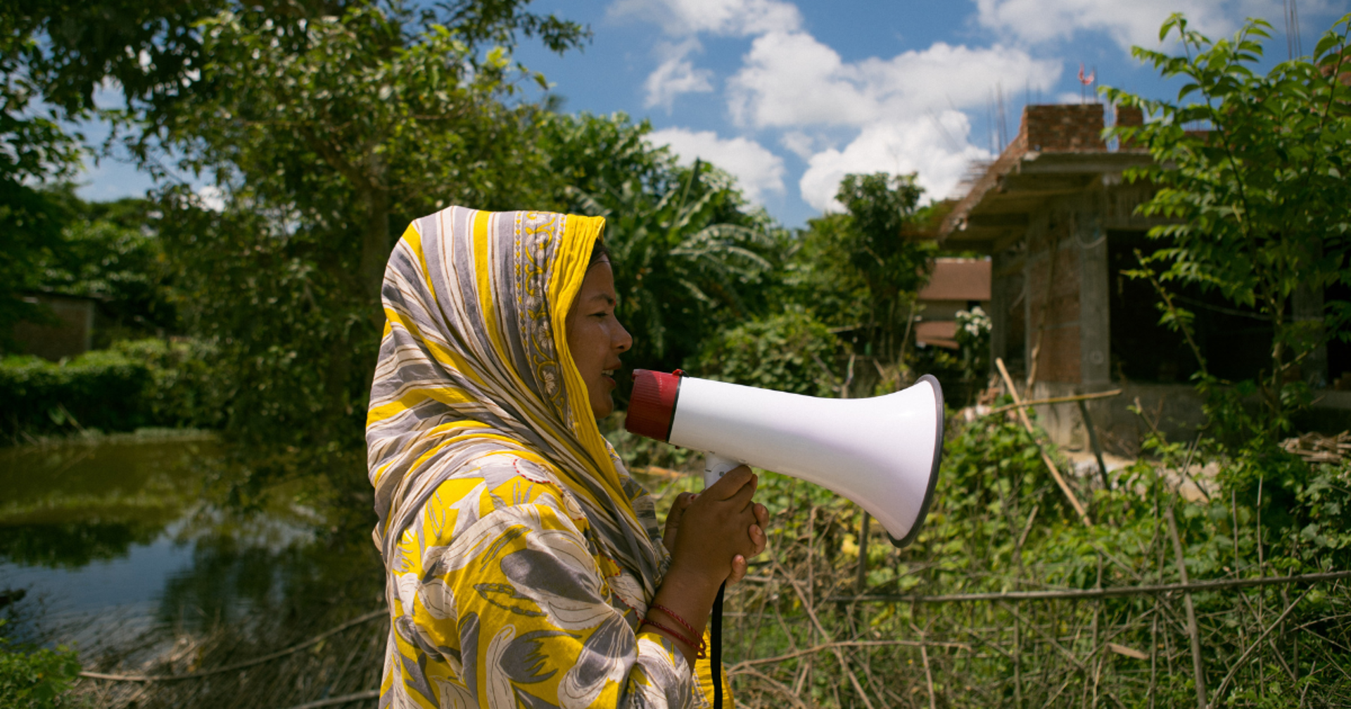 Kolme hymyilevää ihmistä pyöräilee kesäisessä säässä puistossa.