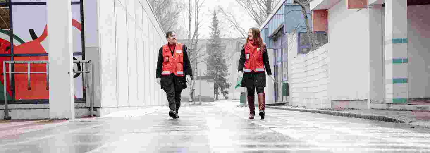 Nuori mies ja nainen Punaisen Ristin vapaaehtoisliiveissä toimittavat kauppa-apua koronan johdosta apua tarvitseville.